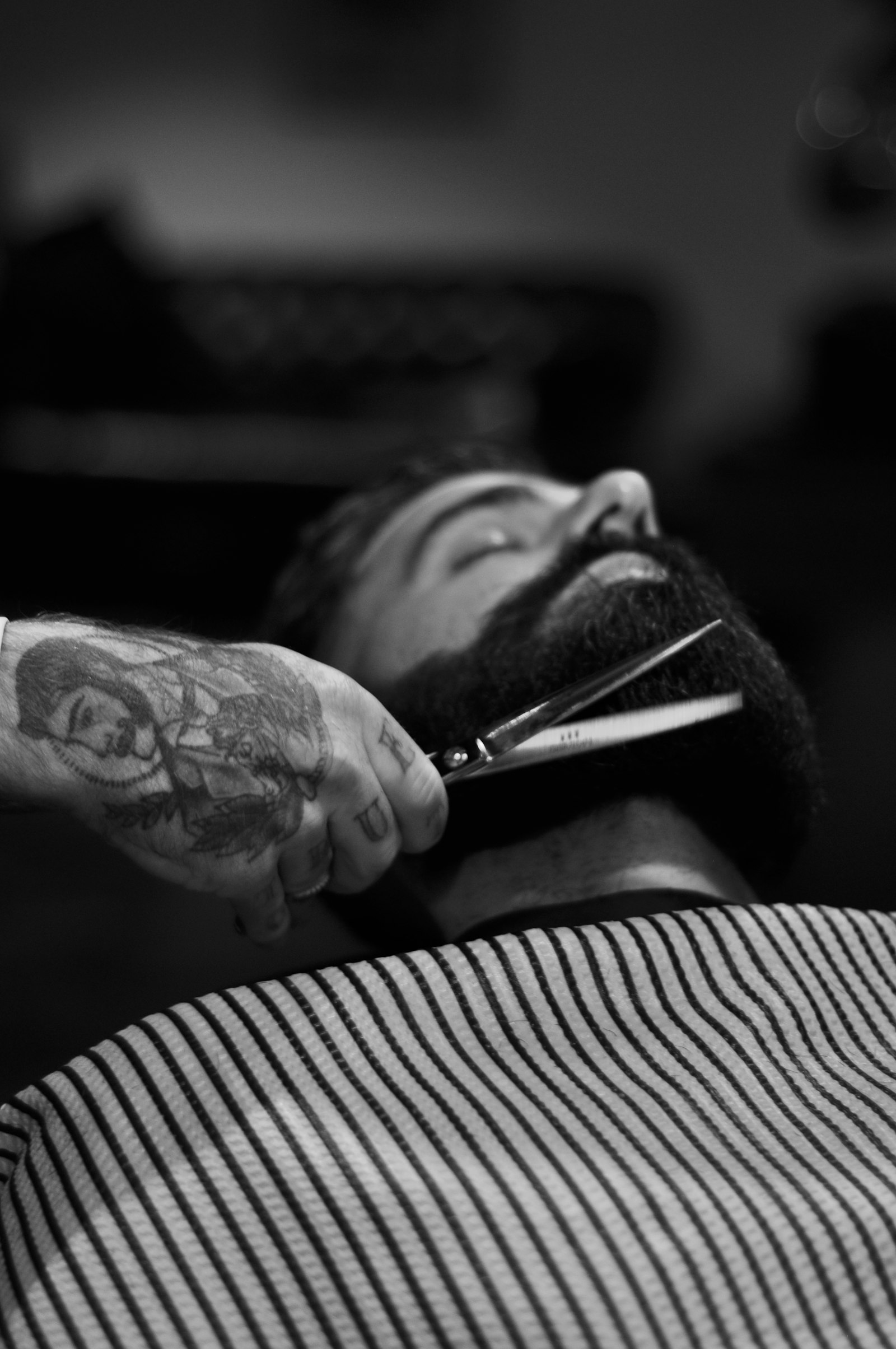 Barber trimming a client's beard with scissors