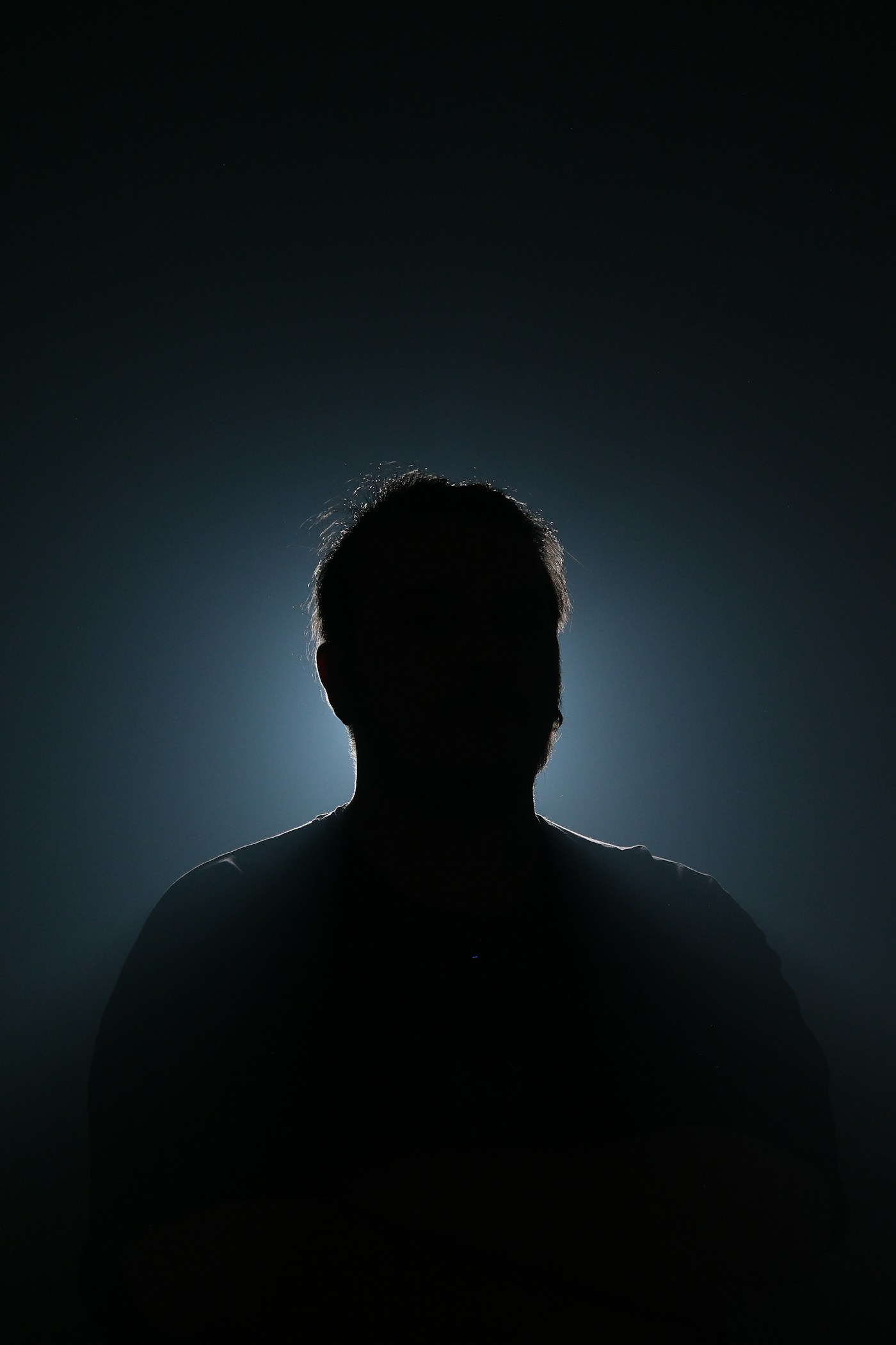 A figure in silhouette against a dim halo of light